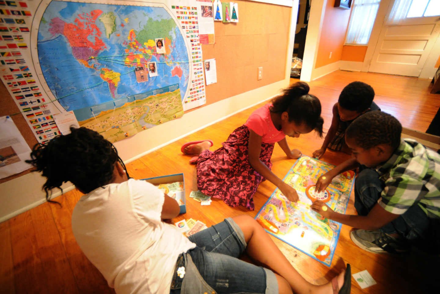 Simone Thomas, Fantazia Savage, Jayden Thomas, and Derrick Wilder play below a Brown House map marking the places their sponsored children live.