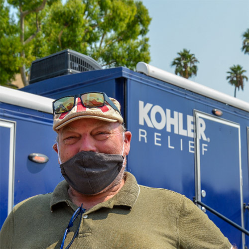 Man wearing mask in front of Kohler relief truck.
