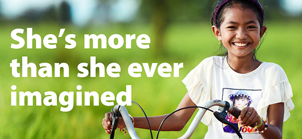 She's more than she ever imagined headline over a photo a girl in Cambodia with her bicycle