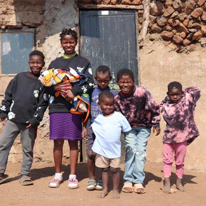 children standing in front of their home