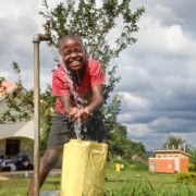 boy laughing while getting water