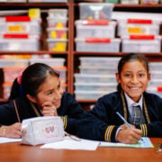 two girls smiling while in school at a desk