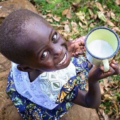 little girl holding cup of milk and smiling