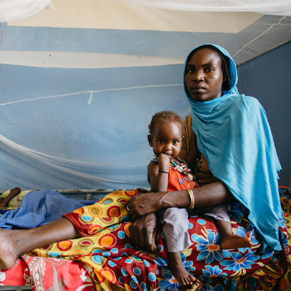 woman and small child sitting under a bed net