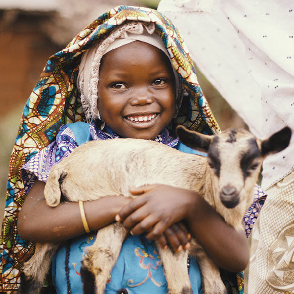 Girl smiles as she holds a baby goat.