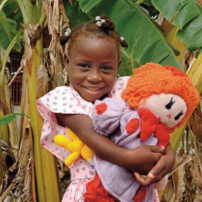 Girl with a smile on her face holds her doll