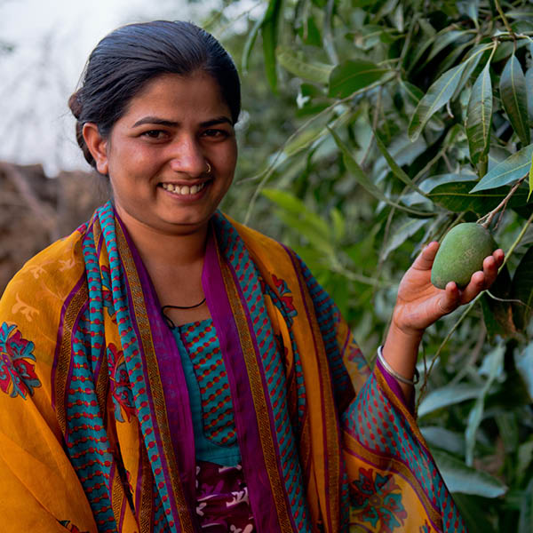 Woman smiles holding fruit hanging from a branch.