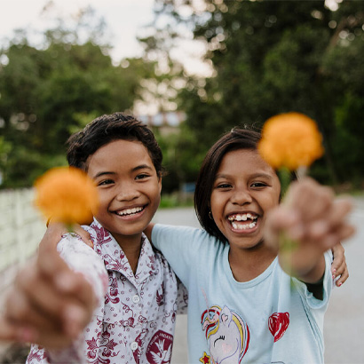 two kids smiling holding flowers