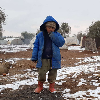 Young boy stands in the cold in winter clothes
