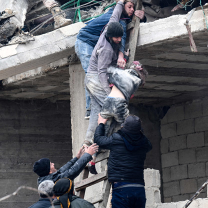 men help a girl descend a ladder from a damaged building after an earthquake hit Turkey and Syria