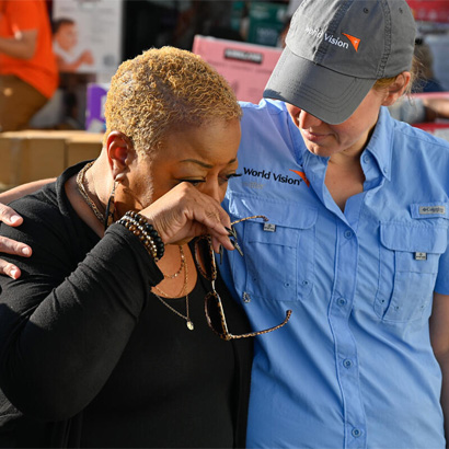 woman putting her hand around another woman who is crying to comfort her