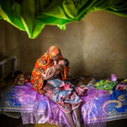 woman holding new born baby on bed