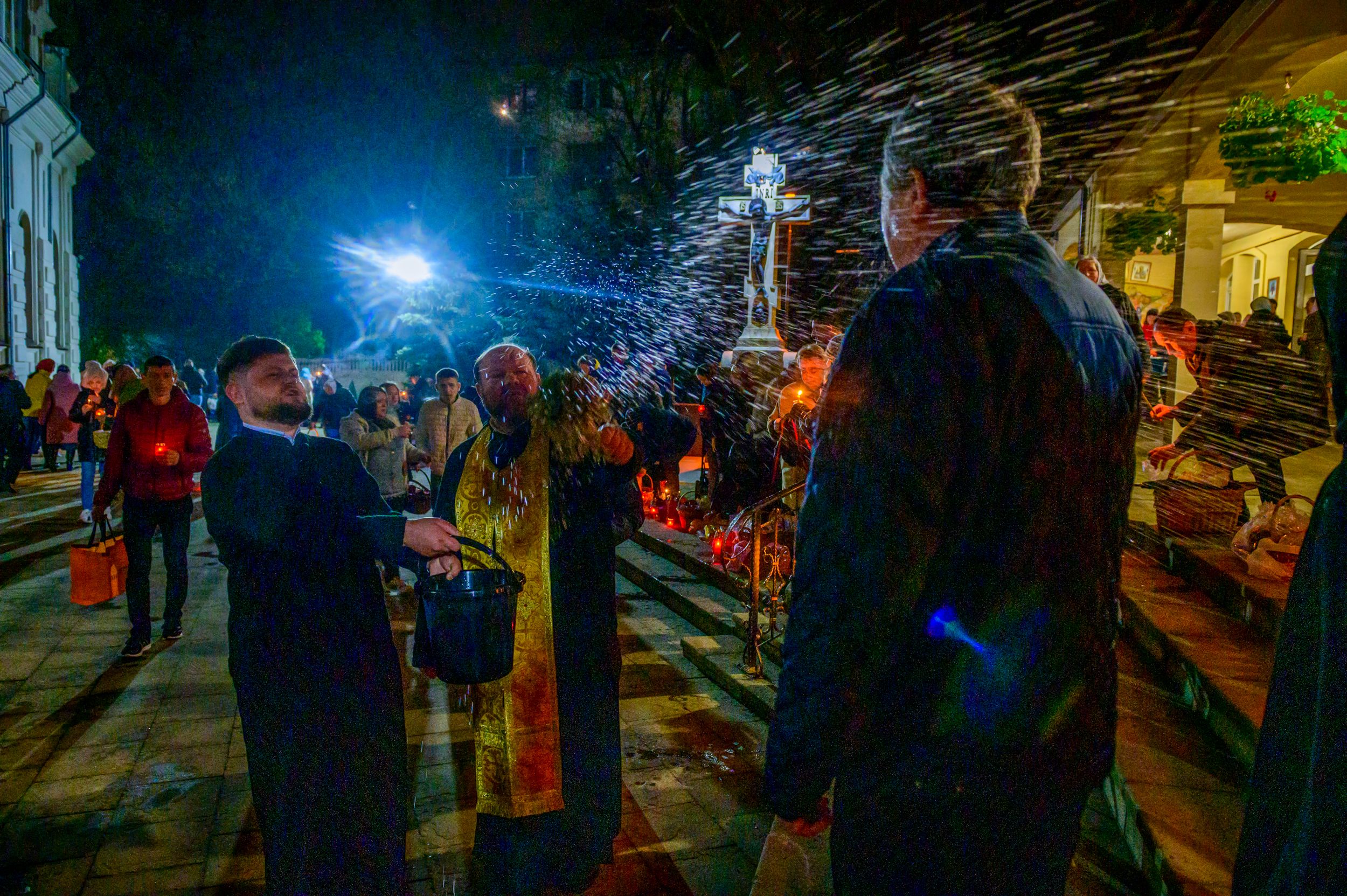 An Orthodox priest blesses parishioners and offerings of food by sprinkling them with holy water during the Easter service. 