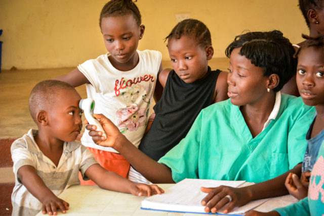 Alima, a nurse, checks 3-year-old Ebola orphan Samuel Batty’s temperature. The boy is one of about 3,500 Ebola orphans in Sierra Leone who have lost one or both parents to Ebola, according to a recent World Bank report. The fight against Ebola is not over. Orphans still need care and responders still need resources to quell the few new cases cropping up week to week and rid the disease from Sierra Leone. (©2015 Sahr Ngaujah/World Vision)