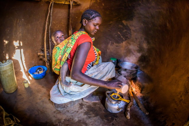 With baby Haron tied to her back Monica makes milk tea for her children's breakfast.