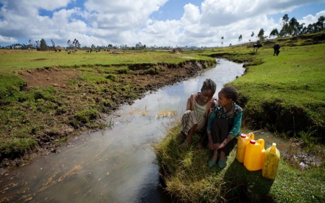 Two girls sit next to the river where they used to get their drinking water but have access to fresh, safe water after World Vision Ethiopia constructed a borehole well in their community in 2011.