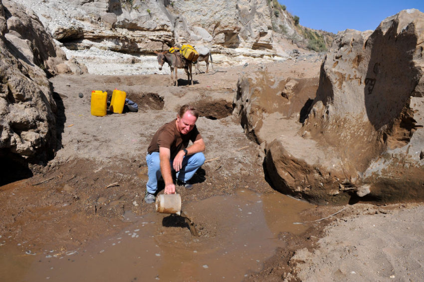 Max Lucado scoops dirty water at a local water source in Ethiopia.