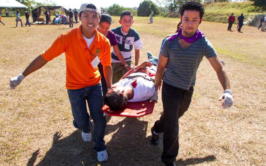 Youth carry a mock victim to an ambulance during disaster response training exercise.