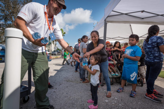 James Orlando, a member of World Vision's Global Rapid Response Team, gives water to a little girl during a relief supplies distribution for Hurricane Irma survivors Sept. 14 at Bethel Assemblies of God Church in Immokalee, Florida.
