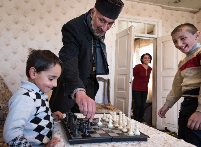 Armenian priest playing chess with a family.