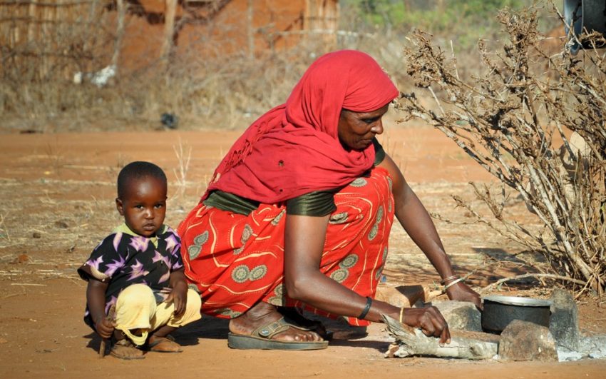 Woman in Kenya cooking outside with her child. Pray for East Africa.