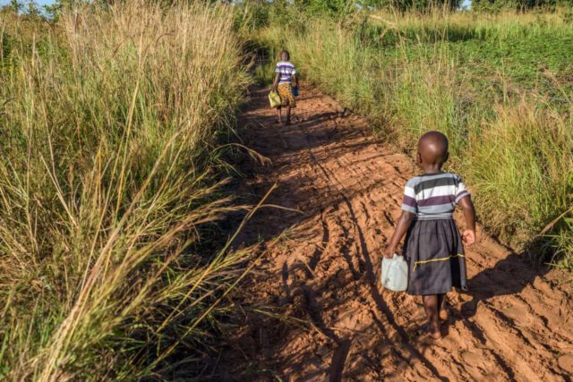 In Morungatuny, Uganda, 5-year-old Grace and 3-year-old Judith start and end their day with walking to gather water for their family. Judith often struggles to keep up with her older sister and has trouble carrying her 1-liter water can. (©2017 World Vision/photo by Jon Warren)