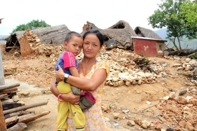 A woman holds her baby amid the ruins of her home after a deadly earthquake.