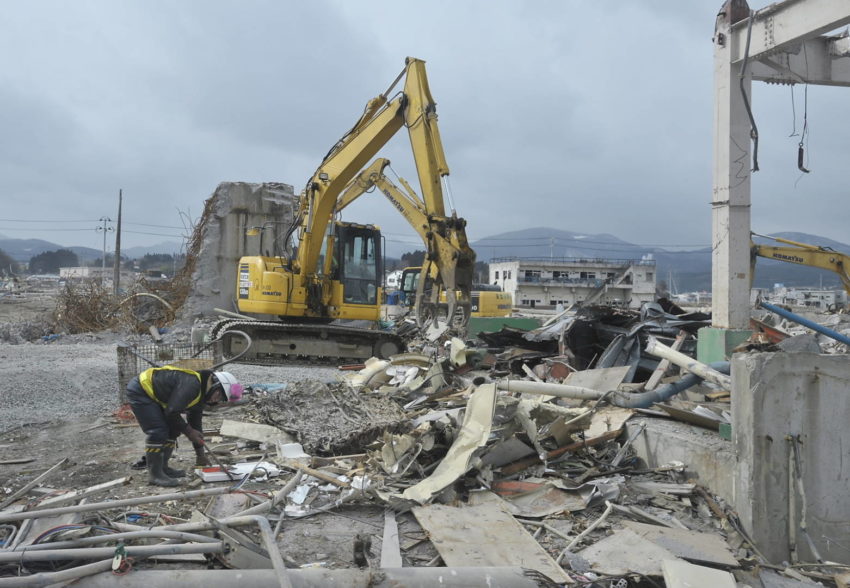 Heavy machinery clears rubble and debris after catastrophic earthquake.