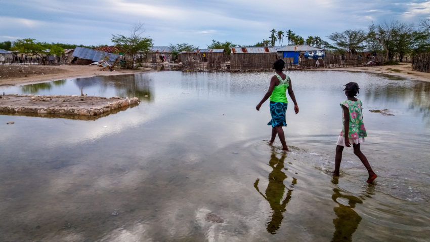 Water inundates Boudain, a community on La Gonâve island, one of the areas hardest hit by Hurricane Matthew on the island nation. Ivonne and her daughter Cindia, 8, walk toward their collapsed home. “I really do not know what I will do,” she says. World Vision supports 100 children in Boudain through sponsorship and is bringing relief supplies. (©2016 Claudia Martinez/World Vision)