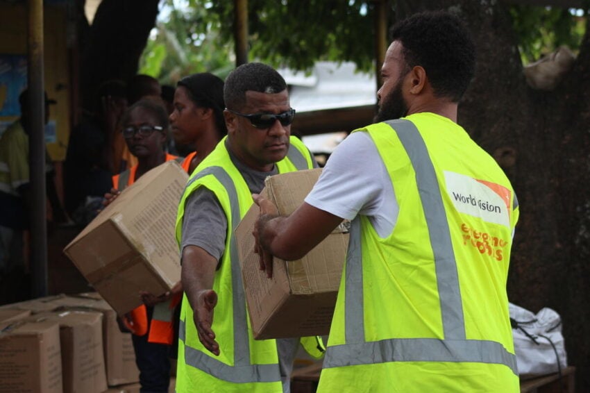 Aid workers lift relief boxes during a post-cyclone aid distribution.