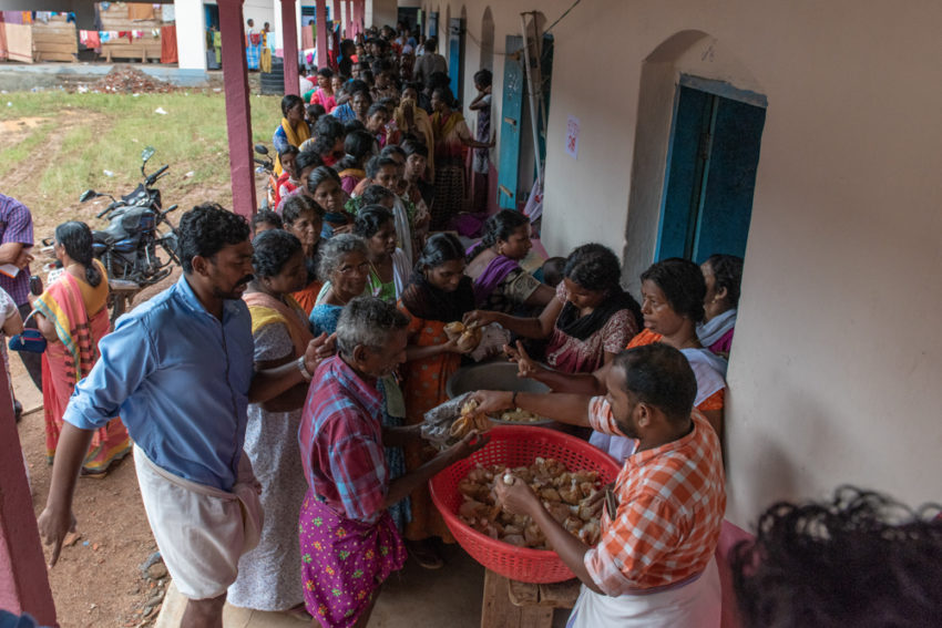 2018 India floods. More than 450 families whose houses have been flooded are taking shelter in a secondary school in Pathanamthitta, Kerala. Representatives of each family stand in long lines to receive food. Heavy monsoon rains led to flooding, and now that dams have been opened every, house in the community is submerged. (©2018 World Vision/photo by Theodore Sam)