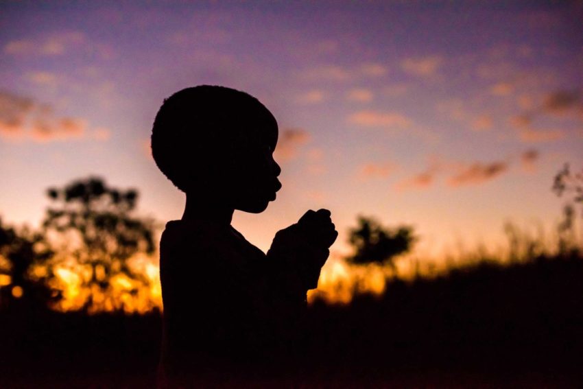 A sponsored child in Zambia is silhouetted against the sky.