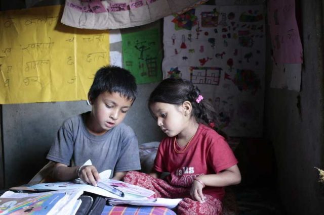 Jhalak, left, reads with his sister at the reading corner his family created in their home in Nepal. Reading corners are part of the literacy program World Vision created to increase literacy rates in Nepal.