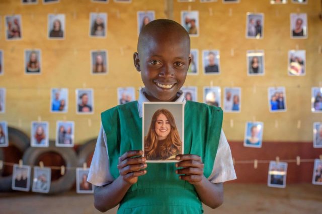 A girl in Kenya holds a photo of her sponsor