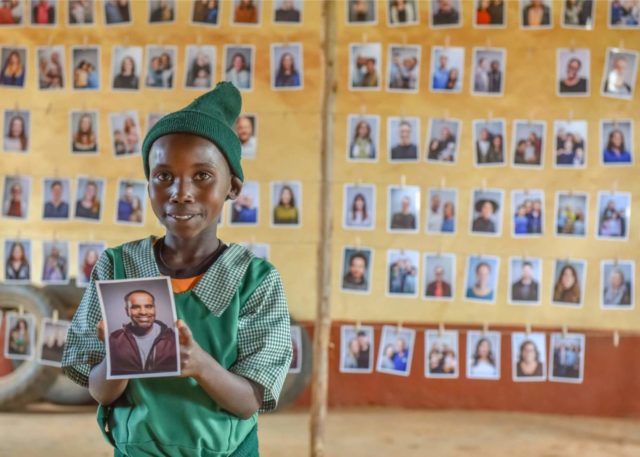 A girl in Kenya holds the photo of a man in Chicago who she chose to be her sponsor.