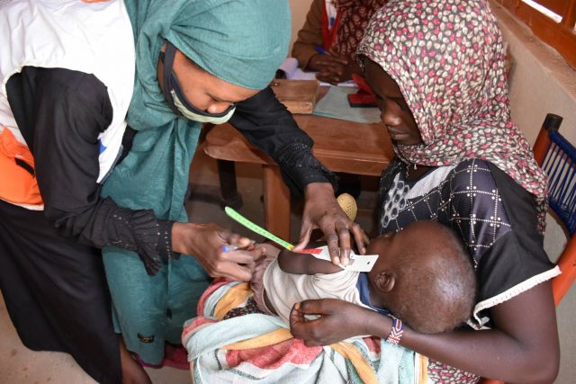 Health worker screens a child for malnutrition in South Darfur, Sudan.