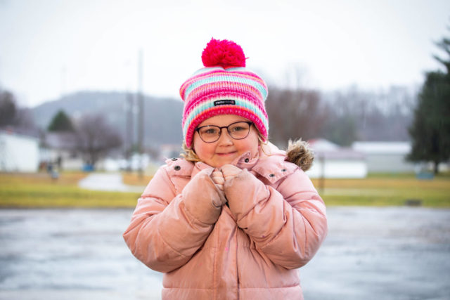 A young girl wearing a winter coat smiles at the camera.
