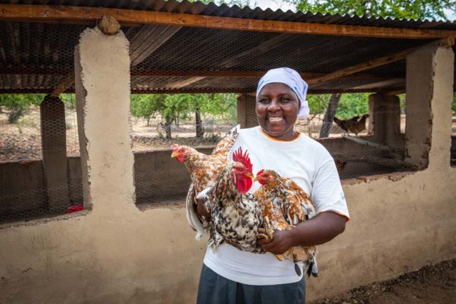 A woman holds chickens.