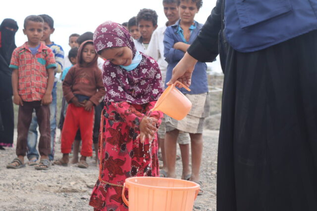 Children line up outside to practice handwashing instructions led by a staff member from Medair, a World Vision partner in Yemen.