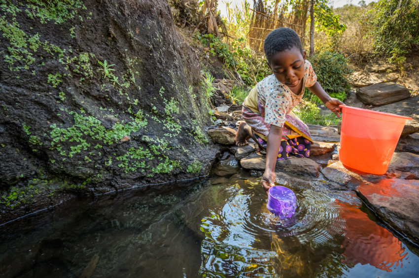 Eight-year-old Ireen dips her cup into a pool in Malawi.
