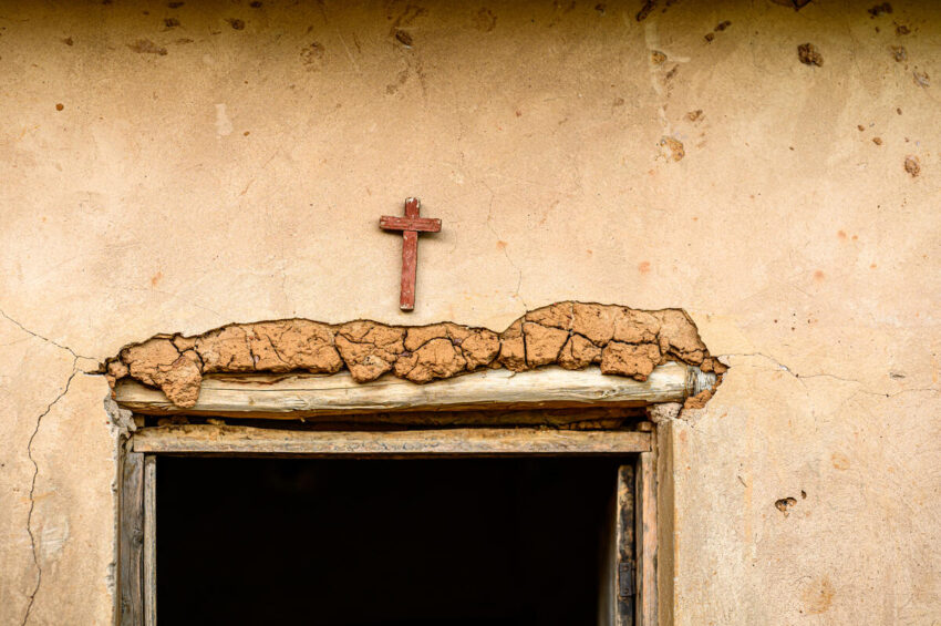 A small wooden cross hangs above a mud-made doorframe in Rwanda.