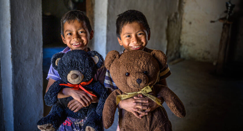 Nine-year-old twins Carlos Hernain and Carlos Joel hug their prized teddy bears, gifts from a visiting church team. The black bear is named Monkey, and the brown bear is Bear. The boys have been World Vision sponsored children for two years. (©2020 World Vision/photo by Jon Warren)