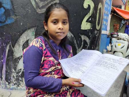 Ashmitha holds her notebook. After losing her father to COVID-19, she wants to study to be a doctor so she can save lives.