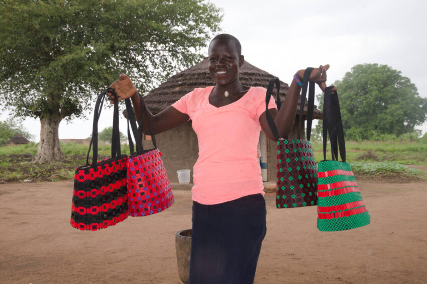An exuberant Dominca models some of the bags that she and other women in the refugee settlement have learned to create in order to provide for their families now and in the future.