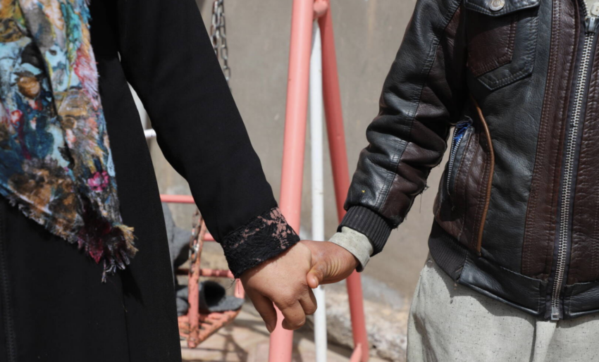A mother and son from Afghanistan hold hands