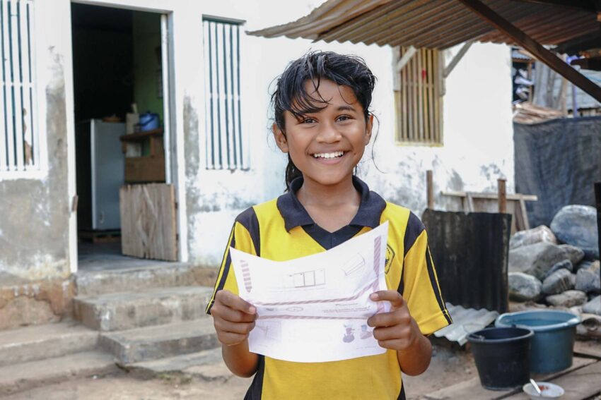 Rahmawati, 10, in Indonesia is excited to get a letter from her World Vision sponsor. A smiling girl in a yellow shirt holds a letter.