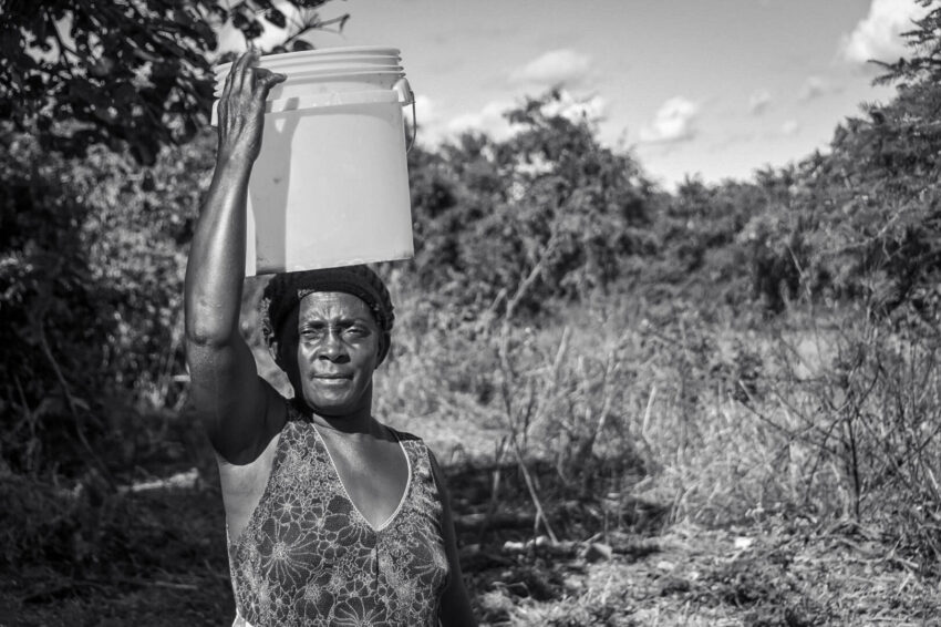 Maves stands with a 20-liter bucket that’s used to collect water