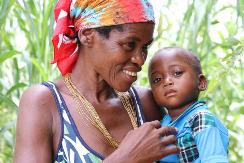 A grandmother in Angola smiles and looks toward her grandson who she holds in her arms.