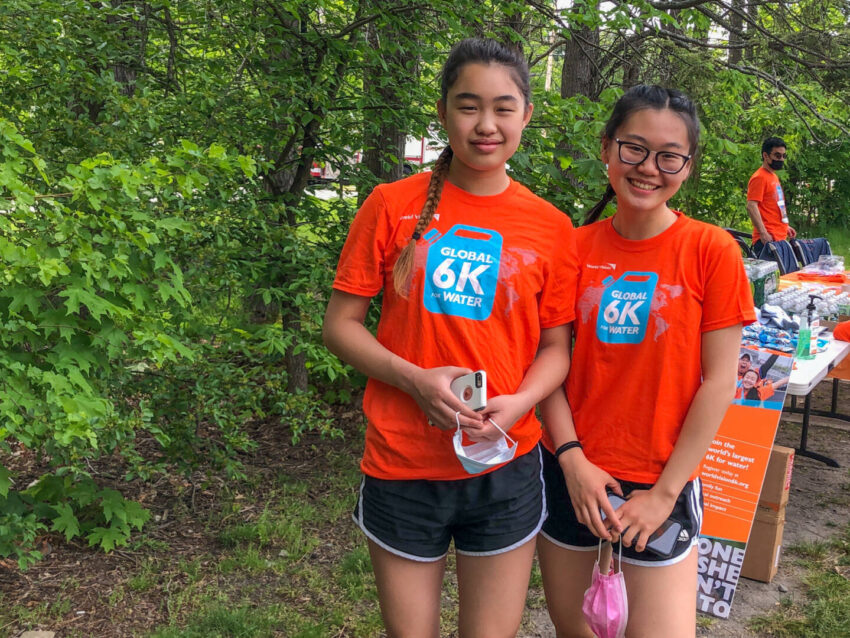 Two teenage girls pose in their bright orange World Vision Global 6K shirts.