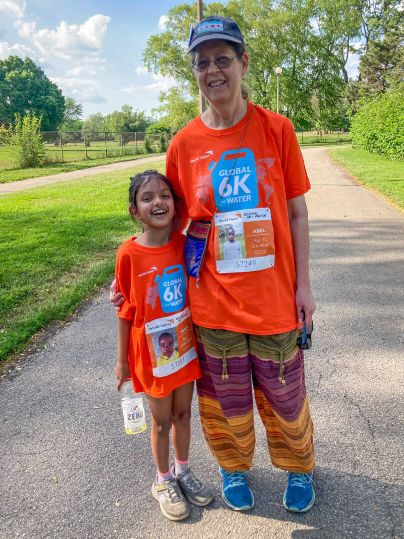 A young girl and her grandma pose with arms around each other, smiling in their orange World Vision Global 6K shirts.